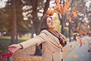 woman closing eyes dancing in leaves