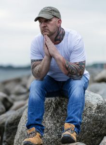 man sitting on rock looking over ocean