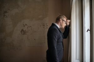 man in suit with forehead leaning on the wall