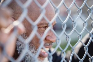 man looking through chain link fence