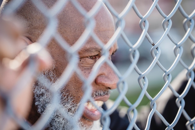 man looking through a chain link fence